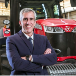 Executivo apresentando implemento agrícola em fábrica